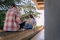 Girls were distracted by something while writing homework. They are sitting on a wall ledge and looking at something Royalty Free Stock Photo