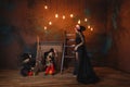 Girls in witch costumes are sitting near the fireplace making a potion, their mother is standing nearby Royalty Free Stock Photo