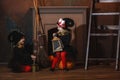 Girls in witch costumes are sitting near the fireplace on pumpkins, one is holding a lantern, the other is making a potion Royalty Free Stock Photo