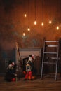 Girls in witch costumes are sitting near the fireplace on pumpkins, one is holding a lantern, the other is making a potion Royalty Free Stock Photo