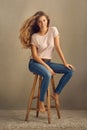 Girls, you should be smiling. Studio shot of a beautiful young woman sitting on a stool against a plain background. Royalty Free Stock Photo