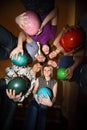 Girls and youths stand in close circle with balls