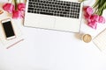 Top view of female worker desktop with laptop, flowers and different office supplies items. Feminine creative design workspace.