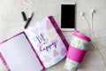 Girly thermos, notebook, phone and headphones on white wooden table Royalty Free Stock Photo
