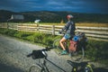 08.18.2019, Giurcuta, Romania: Young woman on a bicycle in a country road landscape with dramatic sky and bright morning light Royalty Free Stock Photo