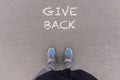 Give Back text on asphalt ground, feet and shoes on floor Royalty Free Stock Photo