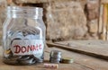 Give donate ,money jar with a label with the word donations on it and wooden ,give donate written text on wooden,coins in jar on Royalty Free Stock Photo