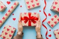 Give a gift on Valentine Day.Valentine gift. Beauty Woman hands holding Gift box with red bow over holiday background Royalty Free Stock Photo