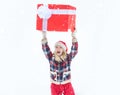 Give gift. Woman in Santa Claus dress giving you big red gift over white snow background. Big gift box. Funny girl push Royalty Free Stock Photo