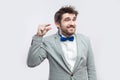 Give me a few more please. Portrait of hopeful handsome bearded man in casual grey suit and blue bow tie standing and looking and