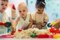 give me that red figure - kids playing with kinetic sand, medium shot blurred background kindergarten concept Royalty Free Stock Photo