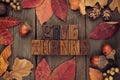 Give Thanks letterpress with frame of autumn leaves over wood