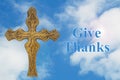 Give Thanks message with a vintage metal cross with clear blue sky