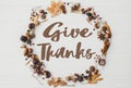 Give thanks text on autumn wreath flat lay on white wood. Happy thanksgiving Seasonal greeting card, handwritten sign.