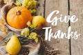 Give thanks text on pumpkin, autumn leaves, flowers, pears, cozy blanket on rustic old wood. Happy thanksgiving Seasonal greeting