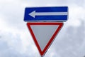 Give way road sign against sky with clouds Royalty Free Stock Photo