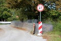 Give way to oncoming vehicles road sign with striped red and white warning sign in front of thick temporary flood protection wall