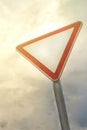 Give way traffic sign dramatically, against the sky and clouds Royalty Free Stock Photo