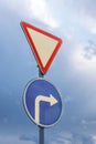 Give way and turn right, against the backdrop of dramatic sky and clouds Royalty Free Stock Photo