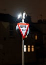 Give way yield traffic sign brightly illuminated at night in dark