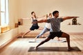 Give your body the gift of balance. a group of young men and women practicing the warrior pose pose during a yoga Royalty Free Stock Photo