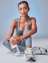 Give your wellness the attention it deserves. Studio shot of a fit young woman drinking bottled water against a grey