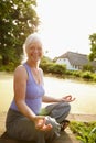 It gives me peace of mind. Portrait of an attractive mature woman sitting in the lotus position in a garden setting. Royalty Free Stock Photo