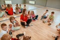 Giving advice. A group of little dancers sitting on the floor gathered around their female dance teacher. Full length Royalty Free Stock Photo