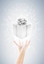 Hand with silver gift box and magic twinkles Royalty Free Stock Photo