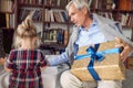 Giving Christmas gift on celebration time- grandfather with gift for his granddaughter