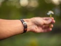 Hand wearing brown leather bracelet giving a daisy Royalty Free Stock Photo
