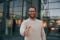 Giving greeting hand. Handsome black man is outdoors near the business building Royalty Free Stock Photo