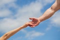 Giving a helping hand. Hands of man and woman on blue sky background. Lending a helping hand. Solidarity, compassion