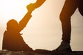 Giving a helping hand. Man helping female climber up a mountain.silhouette of a man gives a hand to a girl on a mountain Royalty Free Stock Photo