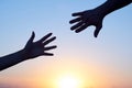 Giving a helping hand. Silhouette Two hands, man and woman, reaching towards each other at sky sunset Royalty Free Stock Photo