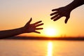 Giving a helping hand. Silhouette Two hands, man and woman, reaching towards each other at sky sunset Royalty Free Stock Photo