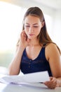 Giving her something to think about. a young woman reading paperwork at home. Royalty Free Stock Photo