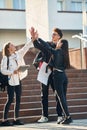 Giving high five to each other. Three young students are outside the university outdoors Royalty Free Stock Photo