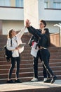 Giving high five to each other. Three young students are outside the university outdoors Royalty Free Stock Photo