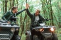 Giving high fives by the hands. Two male atv riders is in the forest together Royalty Free Stock Photo