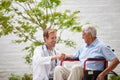 Giving his patient a positive outlook. a male doctor talking to his senior patient whos in a wheelchair outside. Royalty Free Stock Photo