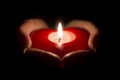 Woman's hands holding a heart shaped candle in the dark. Royalty Free Stock Photo