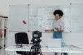 Giving online class. Young afro american female English teacher standing near whiteboard and smiling, explaining rules