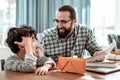 Bearded father giving blue phone his son for talking with mother