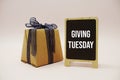 Giving Tuesday text message write on blackboard and gift box on pink background