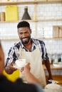 Giving you some happiness in a cup. a handsome young man serving a customer in his coffee shop. Royalty Free Stock Photo