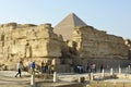 tourists at the location of the pyramids of Giza around ruins of a stone wall and Khufu pyramid is seen Royalty Free Stock Photo