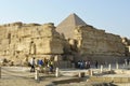 tourists at the location of the pyramids of Giza around ruins of a stone wall and the top of the great pyramid of Giza Khufu Royalty Free Stock Photo