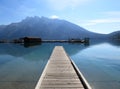 Lake Minnewanka, a wooden shipyard, a boat and a bridge on the water. Mountains in the background.