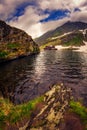 A glacial lake it set high above in the mountains with a house